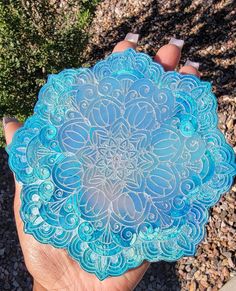 a hand holding a blue glass plate in front of some rocks