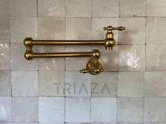 two brass faucets on a white tiled wall