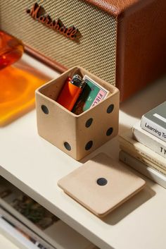 a dice box with some pens and pencils in it