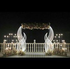 an outdoor wedding setup with candles and flowers on the balcony at night time, surrounded by lights