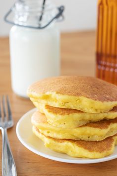 a stack of pancakes sitting on top of a white plate next to a glass of milk