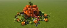 an orange house made out of blocks in the middle of some grass and flowers on top of it