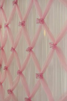 pink sheer curtains with bows hanging on them