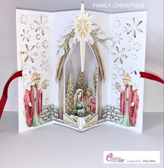 an open christmas card with a nativity scene on it and red ribbon around the edges