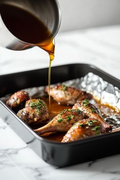 someone pouring sauce on some food in a pan