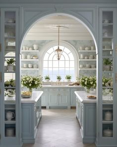 an arched doorway leads to a kitchen with blue cabinets and white countertops, along with flowers in vases