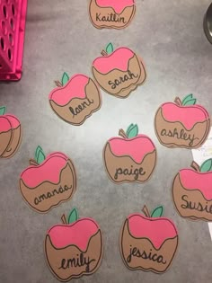 some pink and brown apple shaped cookies on a silver table with words written in them