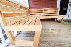 a wooden bench sitting on top of a porch next to a red wall and white door