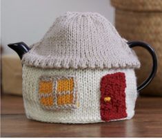 a knitted tea pot cover with a house on it