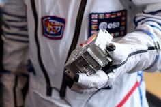 a man in white spacesuit holding a metal object with both hands and wearing gloves