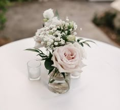 a vase filled with flowers sitting on top of a table next to two shot glasses