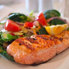 a white plate topped with salmon and veggies