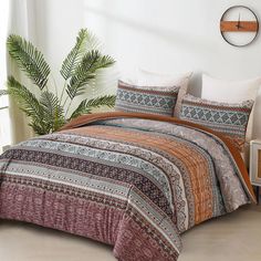 a bed covered in a colorful comforter next to a potted plant and window