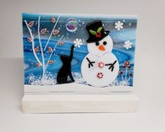 a glass block with a snowman and a black cat on it's side