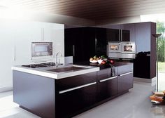 a modern kitchen with black cabinets and stainless steel appliances, including an island style sink