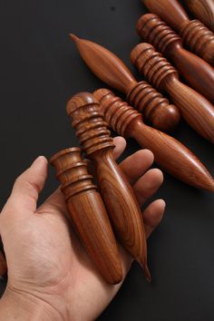 a hand holding several wooden objects on a black surface