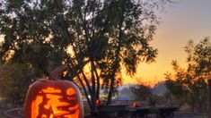 a carved pumpkin sitting on top of a train track next to trees and other items