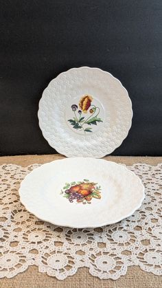 two plates sitting on top of a doily covered tablecloth next to each other