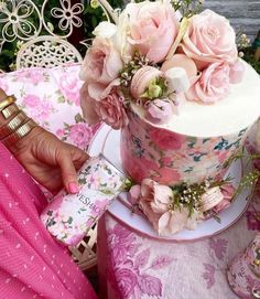 there is a cake with pink flowers on it and a person holding a card in their hand