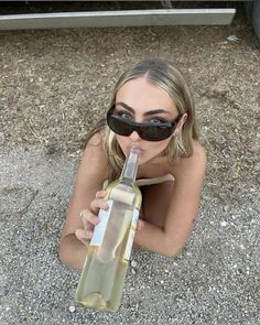 a woman wearing sunglasses is drinking from a wine bottle in the middle of her body