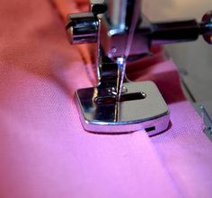 the sewing machine is working on the pink material that's stitching it together