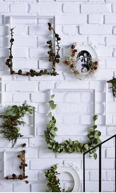 white brick wall decorated with plants and greenery, including an image of a woman's face