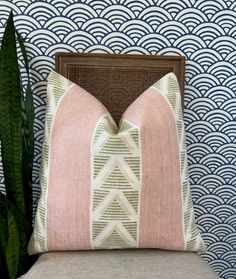 a pink pillow sitting on top of a chair next to a plant