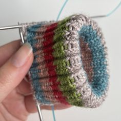 a hand holding a crocheted object with needles in it's palm and the yarn is being knitted