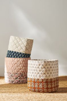 three different colored baskets sitting on top of a wooden table next to each other in front of a white wall