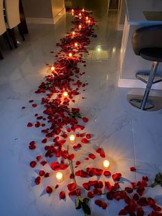 a long line of candles with rose petals on the floor