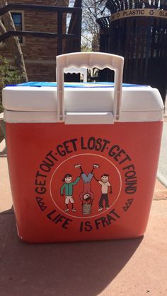 a red cooler sitting on top of a sidewalk