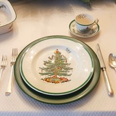 a christmas tree plate and silverware set on a white tablecloth with green trim