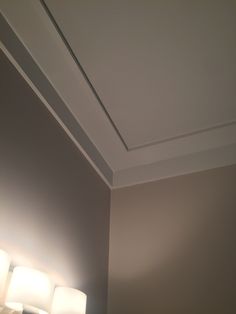 three lights are on in the corner of a room that is painted gray and white