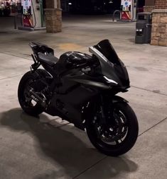 a black motorcycle is parked in front of a gas station with no one around it