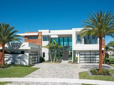 a large white house with palm trees in the front yard and landscaping on both sides