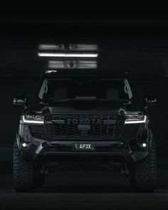 the front end of a black truck in a dark room