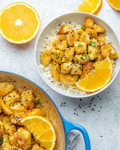 orange chicken and rice in a white bowl next to sliced oranges