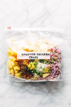 hawaiian chicken taco salad in a plastic bag on a marble countertop with the words hawaiian chicken tacos printed on it