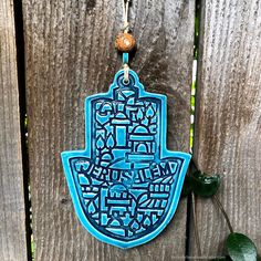 a blue hamsa hanging on a wooden fence