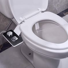 a toilet with the lid up and an appliance attached to it