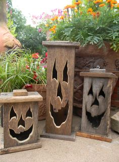 three carved wooden boxes sitting next to each other in front of flowers and potted plants