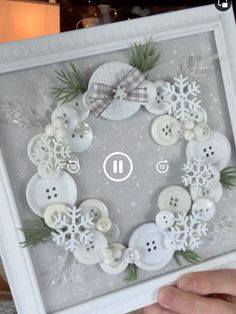 someone holding up a frame with buttons and snowflakes