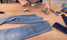 a person cutting up some jeans with scissors and other items on the table next to them