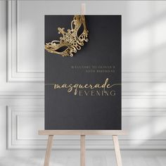 a black and gold masquerade evening card on an easel with a golden mask