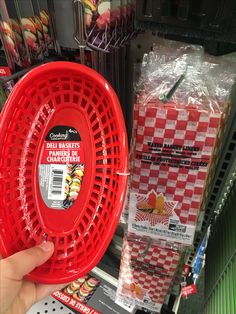 a person holding a red frisbee in front of some other items at a store