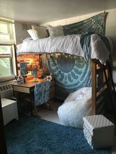 a bedroom with a loft bed, desk and chair next to a blue rug on the floor