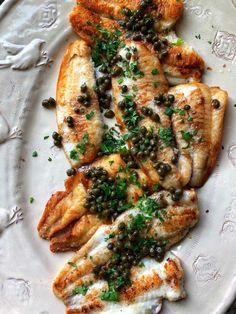 a white plate topped with chicken covered in capers