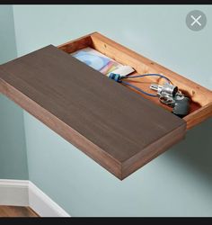 a wooden shelf with various items in it and some cords attached to the wall above