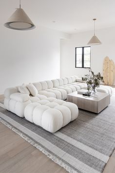 a large white couch sitting on top of a rug in a living room next to a window