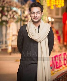 a man wearing glasses and a scarf standing in front of a sign